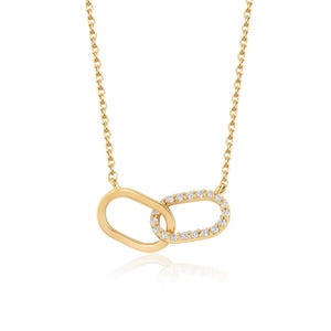 May include: A gold chain necklace featuring two interlocking oval-shaped links as a pendant. One oval link is plain polished gold, while the other oval link is encrusted with small, clear, sparkling stones along its entire outer surface.