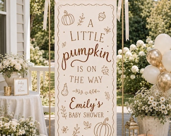 Op de afbeelding: Een verticaal crèmekleurig stoffen spandoek aan een gouden metalen standaard, met bruine tekst A LITTLE pumpkin IS ON THE WAY en Emily's BABY SHOWER, versierd met lijntekeningen van pompoenen, bladeren en een eikel.