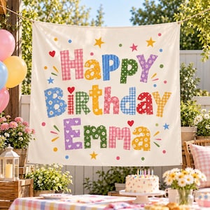 May include: A cream-colored fabric banner featuring the text Happy Birthday Emma in large, multi-colored, patterned letters. The design includes various gingham, floral, and star prints in shades of pink, blue, yellow, green, and red, accented by small colorful stars, hearts, and dots.