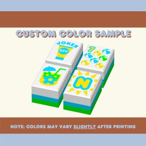 Puede incluir: Cuatro bloques rectangulares blancos con gr&aacute;ficos y texto coloridos, incluyendo "JOKER SPF", una bebida, pelotas de playa y la letra "N". Los bloques tienen rayas azules y verdes. El texto en la parte superior dice "CUSTOM COLOR SAMPLE".
