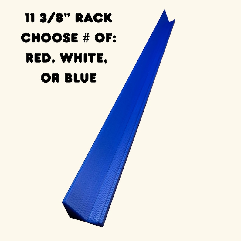 May include: A blue, 11 3/8" long rack with an angled, triangular profile. The text printed on the image reads: 11 3/8" RACK CHOOSE # OF: RED, WHITE, OR BLUE. The object has a smooth, solid finish and is positioned diagonally across the frame.