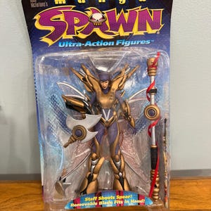 May include: A Manga Spawn Ultra-Action Figure by Todd McFarlane Toys in original packaging. The figure features gold and purple armor, translucent wings, a removable blade, and a staff. The packaging includes the text Spawn and Staff Shoots Spear.