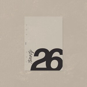 May include: A rectangular beige planner insert page featuring a vertical row of five circular punch holes along the left edge. The page displays the word twenty in a black script font and the large black number 26 printed on the lower right.
