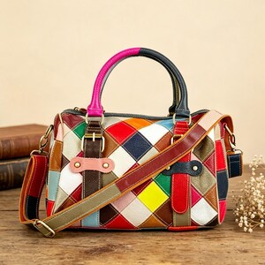 May include: A multi-coloured handbag featuring a patchwork diamond pattern in shades of red, yellow, green, blue, white, and brown. The bag includes a dual-tone handle, a detachable shoulder strap, and decorative leather buckle accents.