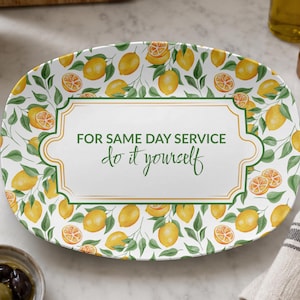 May include: An oval ceramic serving platter featuring a pattern of yellow lemons and green leaves. The center has a white rectangular frame with gold borders and the green text: FOR SAME DAY SERVICE do it yourself, printed in a mix of fonts.