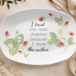 May include: An oval white ceramic serving platter featuring a watercolour illustration of strawberry plants with green leaves, white flowers, and red berries. The centre text reads: I trust the next chapter because I know the auther.