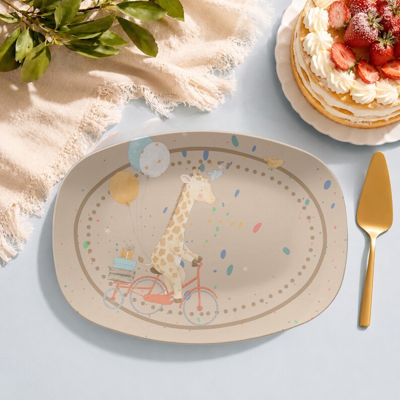 May include: An oval-shaped serving platter featuring a light beige background with a central illustration of a giraffe riding a red bicycle. The giraffe is carrying stacked gift boxes and balloons, surrounded by colourful confetti and a dotted border.