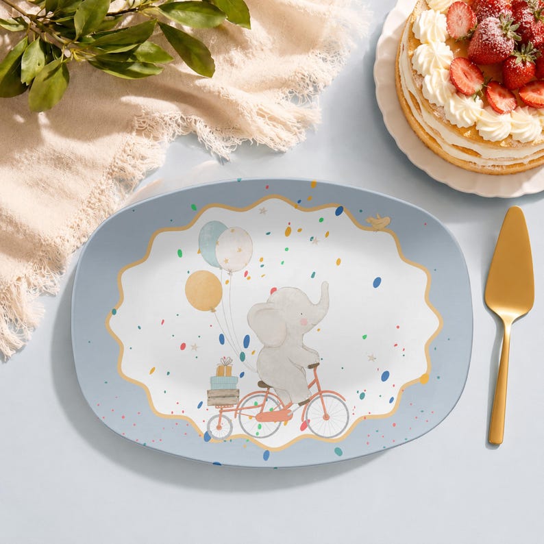 May include: An oval serving platter with a light blue border and a central white scalloped area featuring a cartoon elephant riding a red bicycle. The elephant carries stacked gift boxes and colourful balloons, surrounded by scattered confetti.