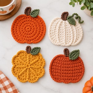 Puede incluir: Cuatro posavasos de ganchillo hechos a mano con forma de calabaza en colores naranja, crema, amarillo y óxido. Cada posavasos presenta un tallo marrón y una hoja verde, con texturas variadas que incluyen patrones circulares y acanalados.