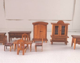 May include: A set of miniature wooden furniture for a dollhouse, including a dresser, a cabinet, a bookcase, a table, and four chairs. The furniture is all made of light brown wood and has a simple, traditional design.