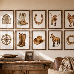 May include: A gallery wall featuring ten framed prints with illustrations of a barn, cowboy boots, a horseshoe, a longhorn, a saddle, a wagon wheel, a cowboy hat, a horse, and a lasso, arranged in two rows above a wooden console table.