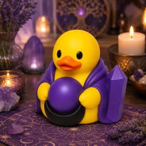 Peut inclure: Une figurine de canard en caoutchouc jaune vêtue d'une cape violette, tenant une sphère violette lisse devant une forme de croissant de lune noir, avec une pointe de cristal violette fixée sur le côté de la cape, des yeux noirs et un bec orange.