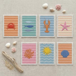 May include: Seven rectangular embroidered patches with scalloped edges, featuring nautical motifs including a red crab, three fish, an orange lobster, a pink starfish, orange coral, a yellow sun, and a blue seashell on various pastel backgrounds.