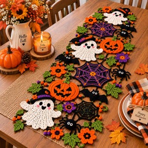 Può includere: Un lungo runner da tavola rettangolare all'uncinetto a tema Halloween, caratterizzato da fantasmi bianchi con cappelli neri, zucche arancioni, ragnatele viola e nere, ragni neri, pipistrelli e foglie verdi in un motivo decorativo.