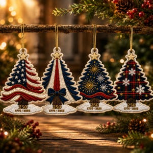 May include: Four embroidered Christmas tree ornaments hanging from a branch. Each features a gold star at the top and a base with the text 250 and 1776-2026. Designs include an American flag, a red and blue pattern, fireworks, and a plaid pattern.