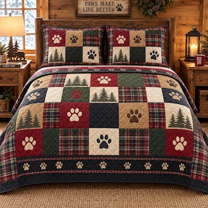 May include: A quilted bedspread and two matching pillow shams featuring a patchwork design of red, green, and navy blue plaid squares, cream squares with paw prints, and green squares with pine tree silhouettes, finished with a dark border.