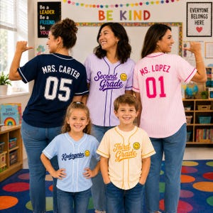 May include: A collection of five button-down baseball jerseys in various colors. The navy jersey reads MRS. CARTER 05, the lavender reads Second Grade with a smiley face, the pink reads MS. LOPEZ 01, the light blue reads Kindergarten, and the cream reads Third Grade.