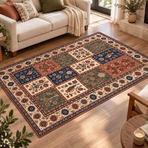 May include: A rectangular area rug featuring a patchwork design of alternating floral and bird motifs in shades of deep blue, forest green, and terracotta red, enclosed by a wide cream-coloured border decorated with repeating floral patterns.