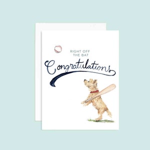 Puede incluir: Una tarjeta blanca con una ilustración de acuarela de un perro sosteniendo un bate de béisbol y una pelota de béisbol volando en el aire. La tarjeta dice "Right off the bat Congratulations".