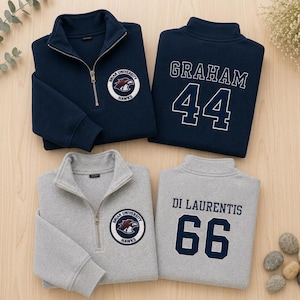 May include: Two quarter-zip sweatshirts in navy blue and heather grey. The front features a circular Briar University Hawks patch. The back of the navy sweatshirt displays the name GRAHAM and number 44, while the grey one shows DI LAURENTIS and 66.