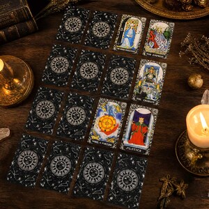 May include: A collection of tarot cards arranged in a grid on a dark wooden surface. The cards feature a black background with white celestial sun and constellation designs, alongside specific cards like The High Priestess and The Empress.
