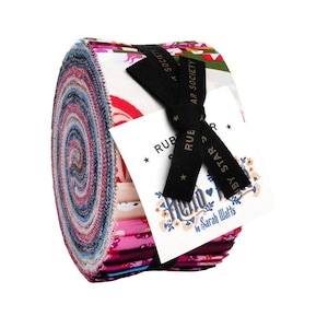 May include: A jelly roll of fabric strips featuring a variety of colourful patterns including pink, red, blue, and white. The roll is secured with a black ribbon printed with stars and the text Ruby Star Society, and a white tag labelled Hello Bear.