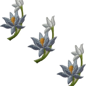 May include: Three identical embroidered patches featuring a blue lotus-style flower with a yellow center, a green stem, and a smaller white bud extending upward. The embroidery uses detailed stitching to create texture and depth on each floral motif.