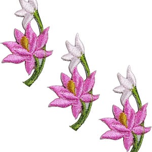 May include: Three embroidered patches featuring a pink flower with a yellow center and a white bud on a green stem. The design shows detailed stitching with vibrant pink petals, a bright yellow stamen, and a white flower bud at the top.