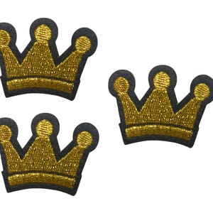 May include: Three embroidered crown patches featuring a metallic gold thread finish and a solid black border. Each crown design displays three distinct points topped with small circular details, showcasing a consistent texture and shape throughout.