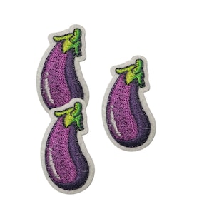 May include: Three embroidered patches shaped like eggplants, featuring a deep purple body with a bright green stem and a white border. The patches are arranged with two stacked vertically on the left and one positioned to the right.