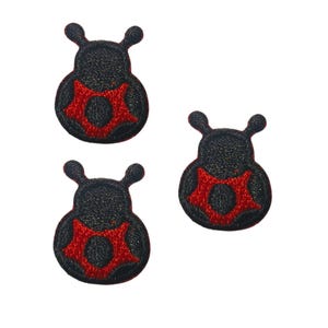 May include: Three embroidered patches shaped like stylized insects, each featuring a black body with two antennae and a prominent red star-like pattern centered on the lower portion. The patches have a textured, stitched appearance throughout.
