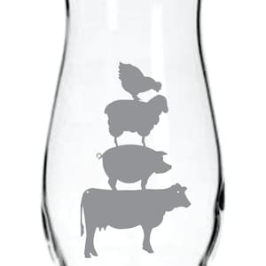 May include: A clear glass vase with a gray silhouette of a cow, pig, sheep, and chicken stacked on top of each other.