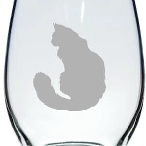 May include: A clear glass wine glass with a gray silhouette of a cat sitting with its tail curled around its body.
