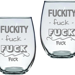 May include: Two clear glass wine glasses with the text "F*CKITY - f*ck - F*CK F*CK" etched on them.