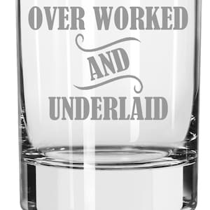 May include: A clear glass tumbler with the text "OVER WORKED AND UNDERLAID" etched in grey.