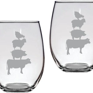 May include: Set of two clear glass wine glasses with a design of a cow, pig, sheep, and chicken stacked on top of each other. The design is etched into the glass.