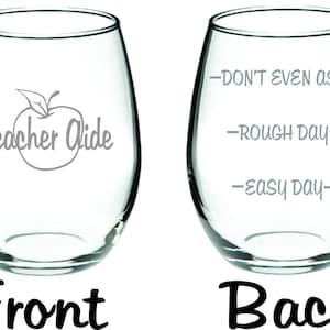 May include: A clear glass wine glass with the text "Teacher Aide" and an apple graphic on the front. The back of the glass has the text "Don't even ask", "Rough day", and "Easy day" in a vertical line.