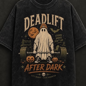 May include: A black acid-wash t-shirt featuring a graphic of a ghost in a beanie lifting a barbell. The text reads DEADLIFT AFTER DARK, STRONG BODIES DON'T DIE, and LIFT HEAVY STAY HAUNTED. The design includes a full moon, pumpkins, and a tombstone.