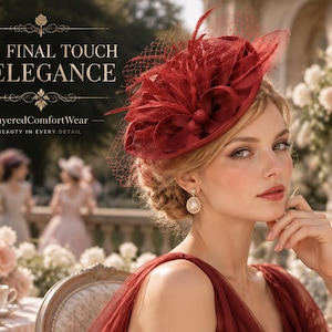 Puede incluir: Un tocado fascinator de color rojo intenso con bucles de tela, plumas y un velo de malla fina. El texto dice THE FINAL TOUCH OF ELEGANCE y LayeredComfortWear BEAUTY IN EVERY DETAIL. El tocado se combina con pendientes colgantes de perlas.