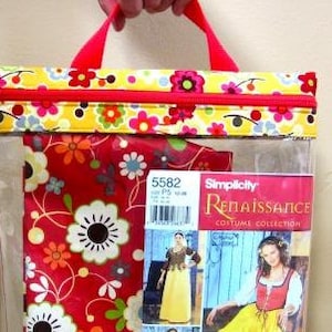 May include: A clear plastic bag with a yellow and red floral print and a red zipper. The bag has a handle and contains a red and white floral fabric and a Simplicity Renaissance Costume Collection pattern.