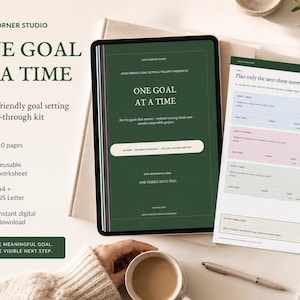 Puede incluir: Un kit digital de establecimiento de objetivos titulado One Goal At A Time, mostrado en una pantalla de tableta y una página impresa. La interfaz verde oscuro presenta indicaciones de texto para planificar tres pasos y secciones.