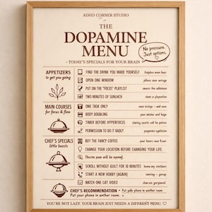 Może przedstawiać: Oprawiony wydruk zatytułowany The Dopamine Menu, z jasnobeżowym tłem oraz ciemnobrązowym tekstem i ikonami. Menu zawiera kategorie takie jak Appetizers, Main Courses i Chef's Specials z różnymi zadaniami dla mózgu.