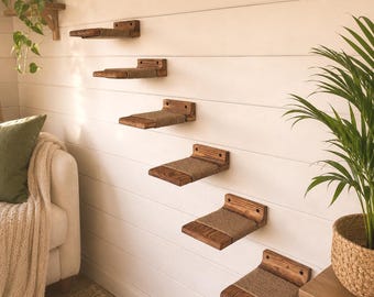 May include: A set of six wall-mounted wooden shelves arranged in a staggered staircase pattern. Each shelf features a dark stained wood base with a central section wrapped in textured tan sisal rope, designed for mounting to a flat vertical surface.