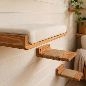 Detailed view of the wooden wall mounted cat bed with soft cream cushion and natural wood grain.