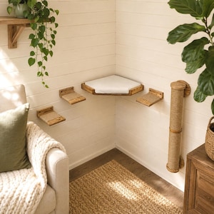 May include: A wall-mounted cat furniture set featuring a large triangular corner platform with a white cushion, two smaller rectangular steps with tan sisal rope surfaces, and a vertical cylindrical scratching post wrapped in tan sisal rope.