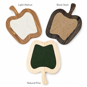 May include: Three apple-shaped wooden wall hangings with rope centers. One is light walnut with white rope, one is black stain with tan rope, and one is natural pine with dark green rope. Text labels read Light Walnut, Black Stain, and Natural Pine.