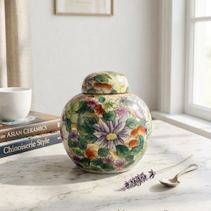 May include: A round porcelain ginger jar with a matching lid, featuring a colourful millefiori floral pattern in shades of purple, green, orange, and yellow. The text on the image reads: VINTAGE CHINESE MILLEFIORI GINGER JAR 1980s | MULTICOLOR PORCELAIN.