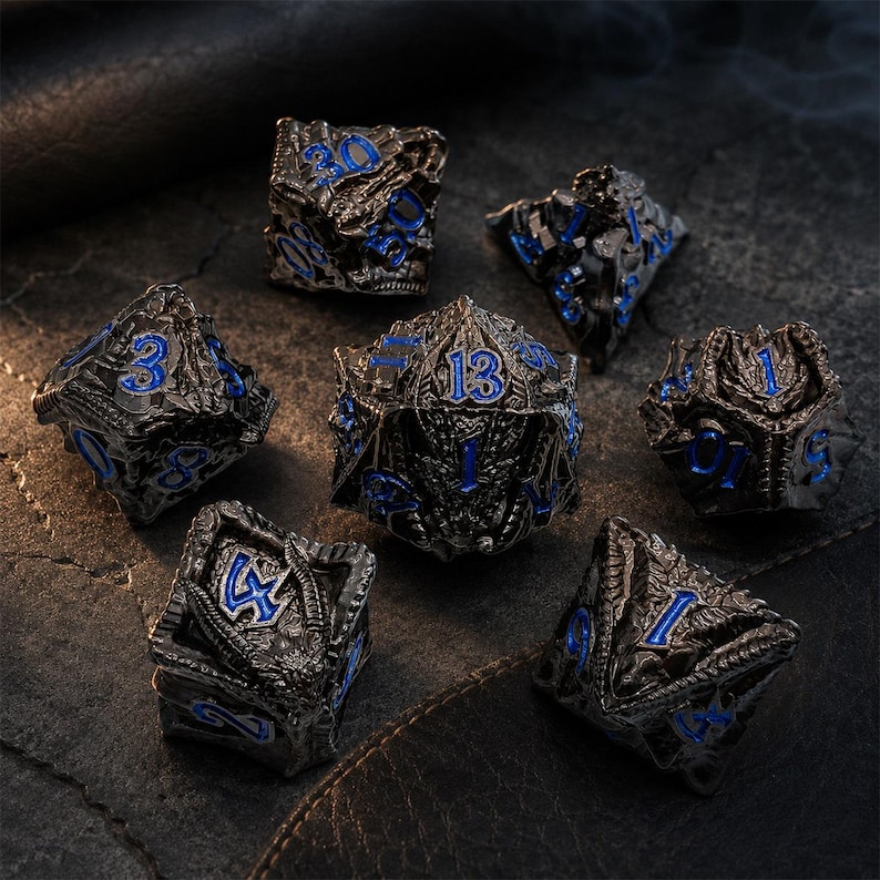 Seven-piece black metal DND dice set with vivid blue numbers and detailed dragon-inspired carvings. The polyhedral dice are arranged on a dark stone and leather surface with the D20 centered.