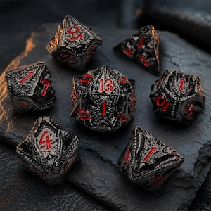Seven-piece glossy black dragon-themed metal DND dice set with bold red numbers and sculpted scales, wings, and dragon details. The polyhedral dice are displayed on a dark textured stone surface.