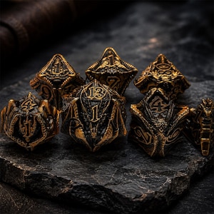 Seven-piece antique bronze and black metal DND dice set featuring raised numbers, dragon heads, wings, scales, and fantasy details. The polyhedral dice are arranged on a rugged dark stone slab.